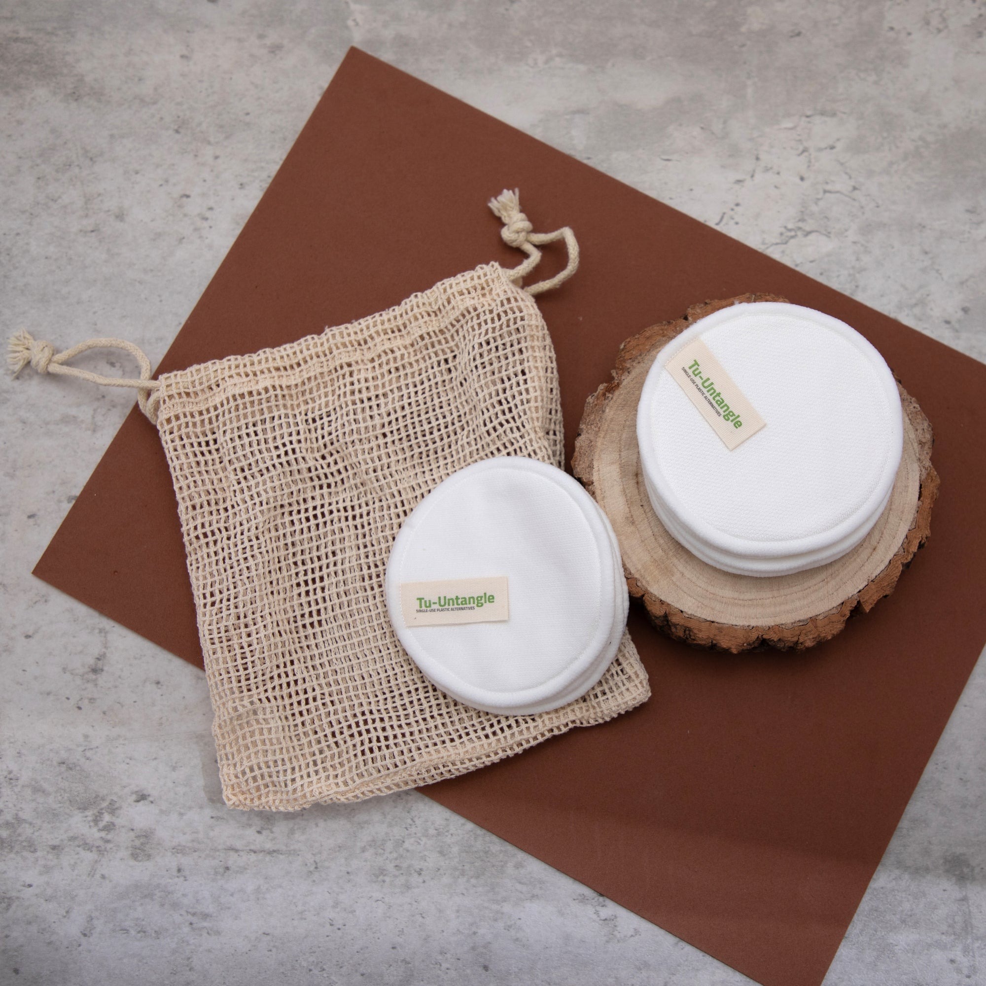 Reusable makeup remover padswith a mesh bag for laundry and wooden block in the background.