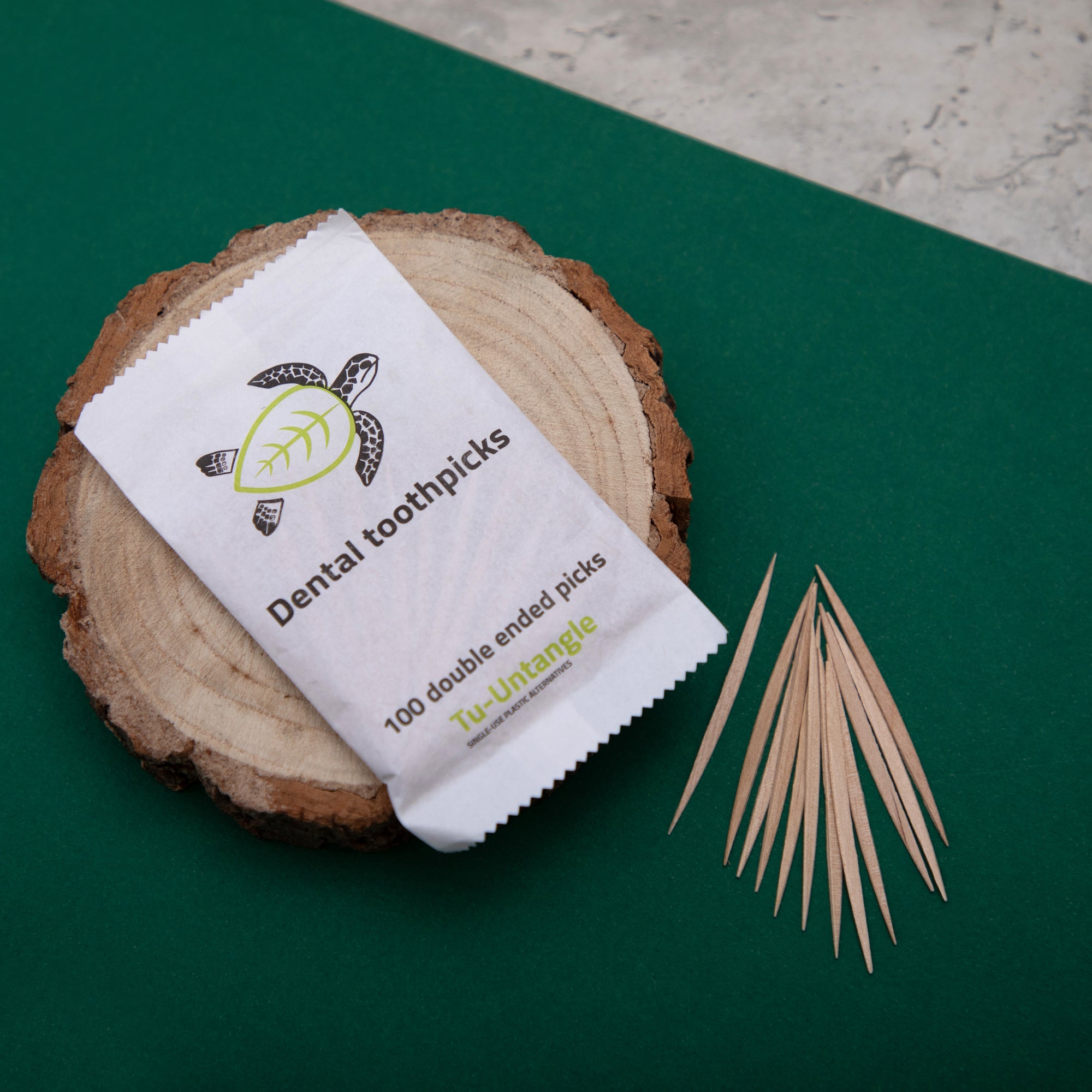 Dental toothpick package on a wooden block with a green background