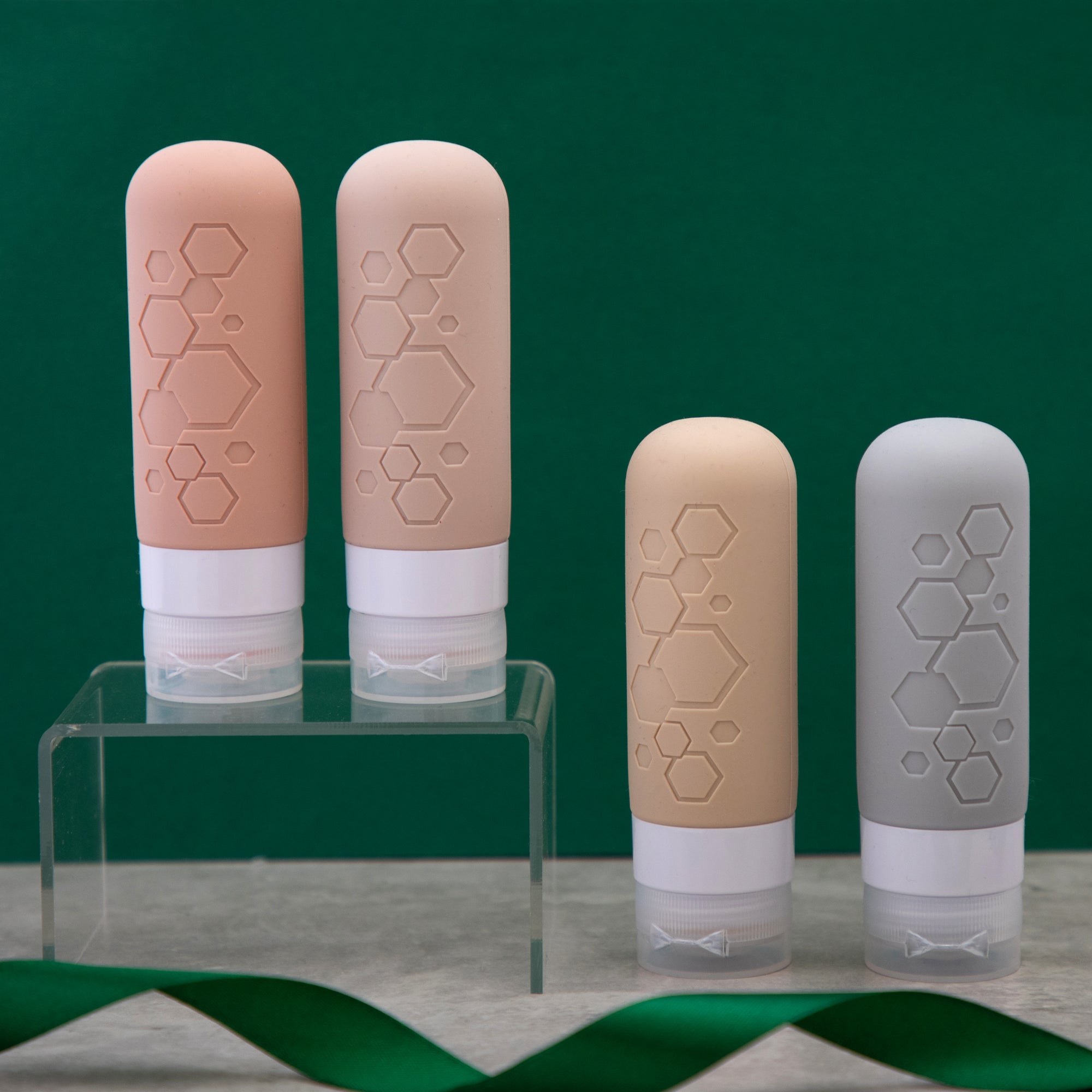 Four containers for liquids for traveling with hexagonal patterns on a green background